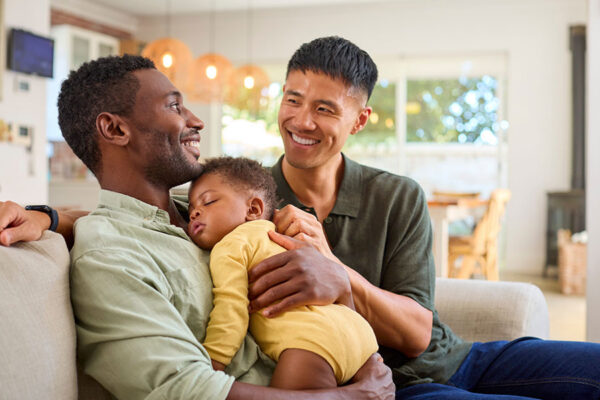 Two dads joyfully hold their baby