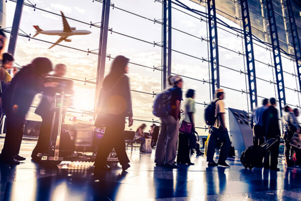 Travelers walking past large airport windows