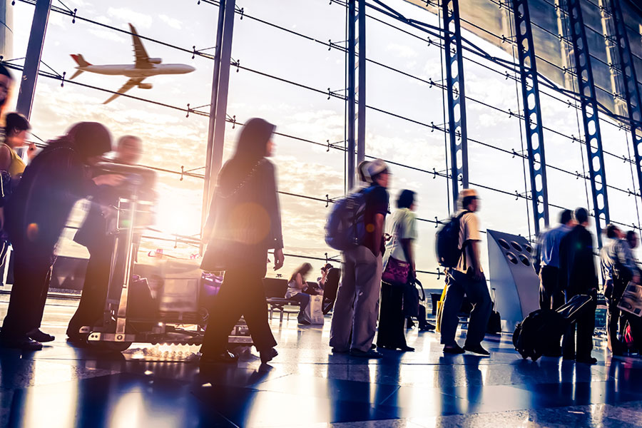 Travelers walking past large airport windows