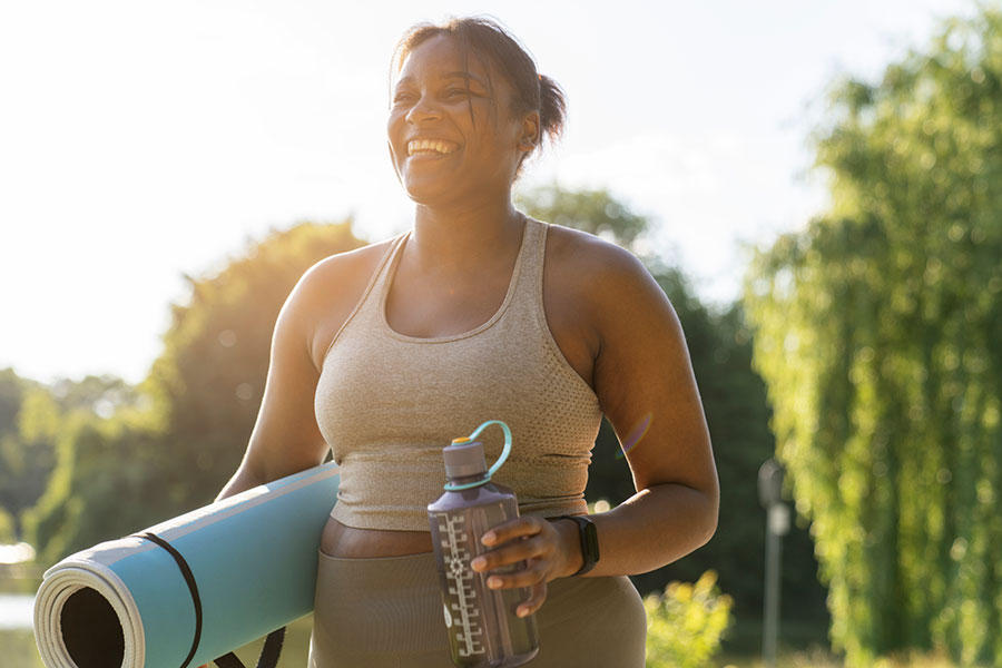 Woman in park with yoga mat and water bottle