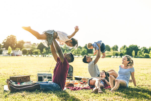 Two dads lift their children overhead "airplane" style